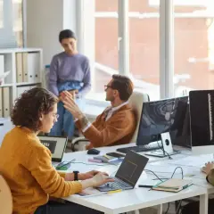 Zespół dyskutuje o regulaminie wynagradzania, pracując przy komputerach w nowoczesnym biurze.