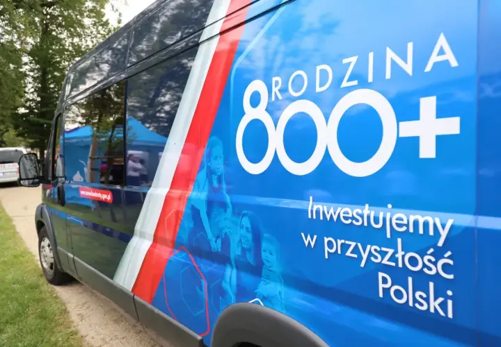 Niebieski bus z napisem "RODZINA 800+" i hasłem "Inwestujemy w przyszłość Polski". Obok rodziny, symbolizującej program 800 plus zmiany.