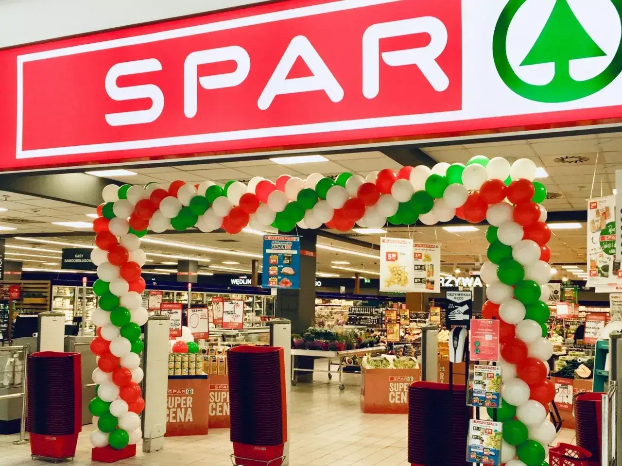 Uroczyste otwarcie sklepu SPAR z łukiem z balonów w barwach narodowych. Akwizycja i świętowanie nowego miejsca na mapie handlowej.
